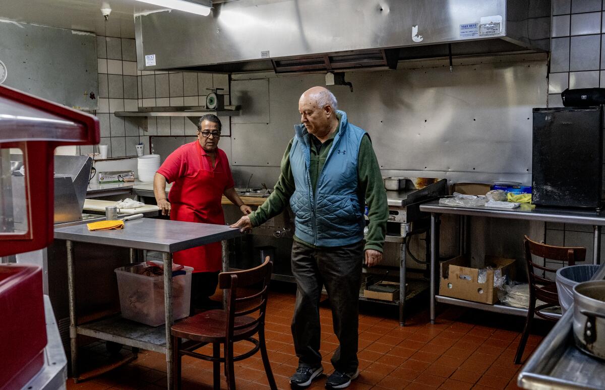 Owner Samuel Solis talks with one of his chefs in the kitchen of his family owned restaurant Taco Boy.