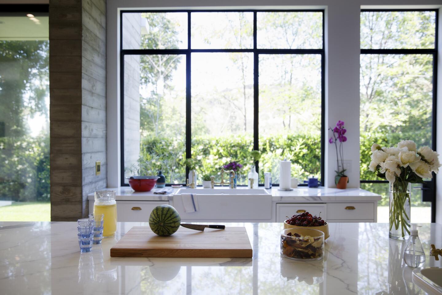 Custom steel windows, powder-coated black, connect the kitchen to the outdoors.