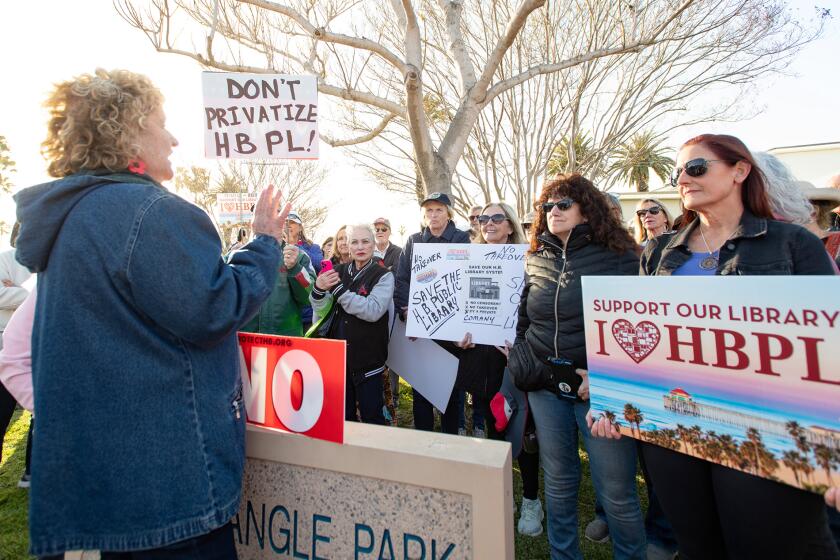 Organizer Cathey Ryder, left, addresses over 100 people participating in a demonstration in protest of plans to privatize Huntington Beach's libraries and create a children's book review board in Huntington Beach on Friday.
