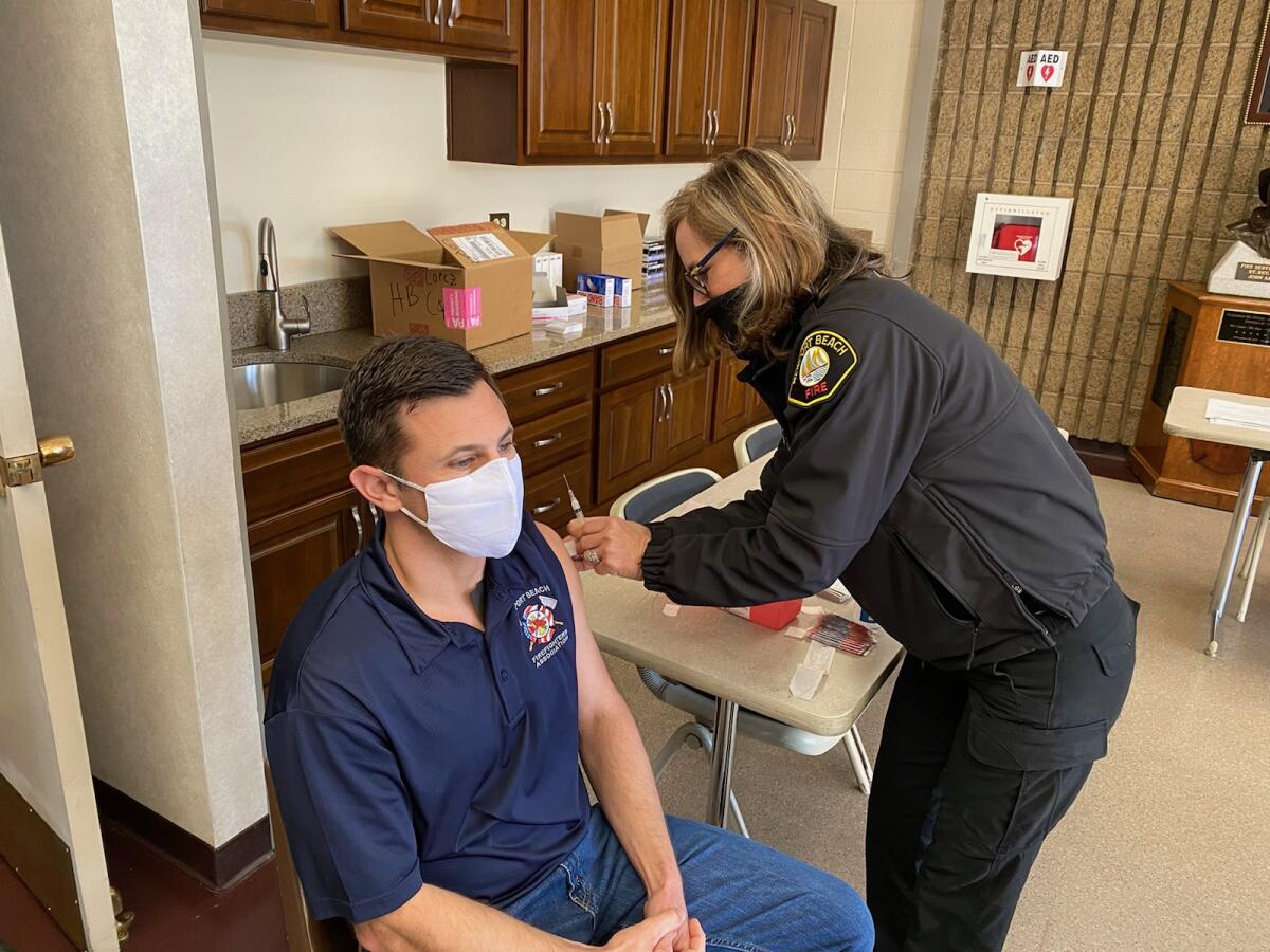 Newport Beach Fire Department EMS Division Chief Kristin Thompson, right, vaccinates Bobby Salerno, left.