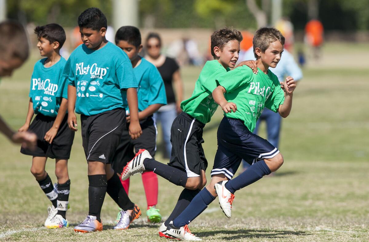 Newport Harbor Heights' Luke Harner congratulates Jack Del Signore after he scored a goal on a penalty kick against Wilson in a 3-4 Gold Division game during the opening day of the 15th annual Daily Pilot Cup on Tuesday.