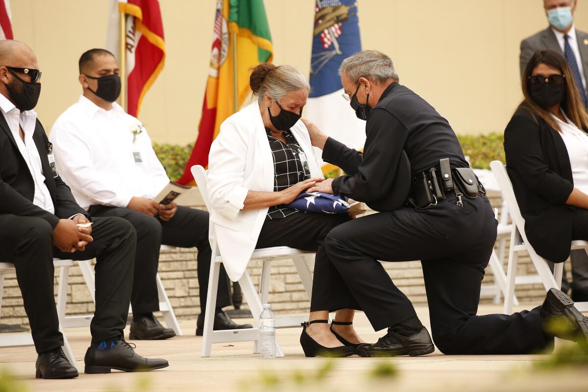 LAPD Chief Michel Moore presents the U.S. flag to Maria Martinez while others sit near her