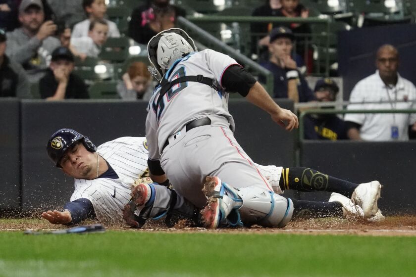 Milwaukee Brewers' Luis Urias, left, is tagged out at home by Miami Marlins' Jacob Stallings during the 10th inning of a baseball game Sunday, Oct. 2, 2022, in Milwaukee. (AP Photo/Aaron Gash)