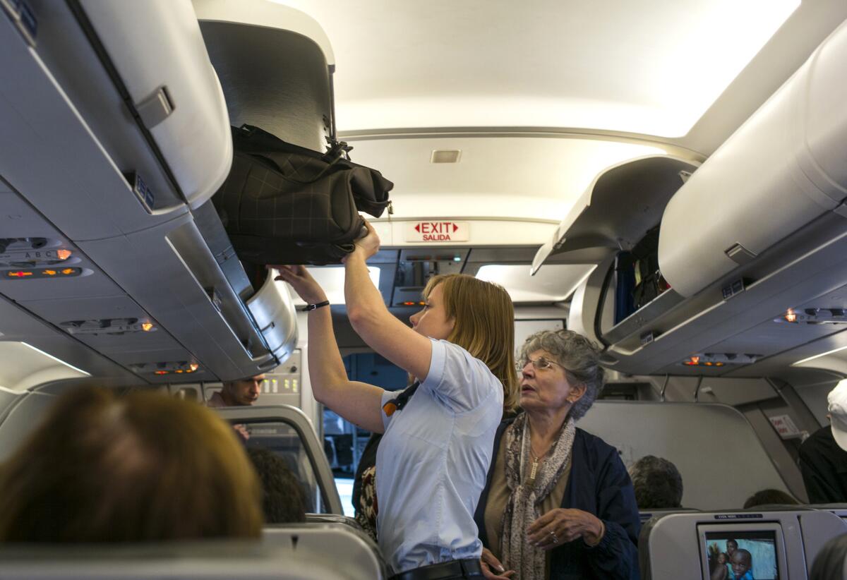 A passenger on a JetBlue Airways flight in June at New York's JFK International Airport receives help with her carry-on luggage from an flight attendant.