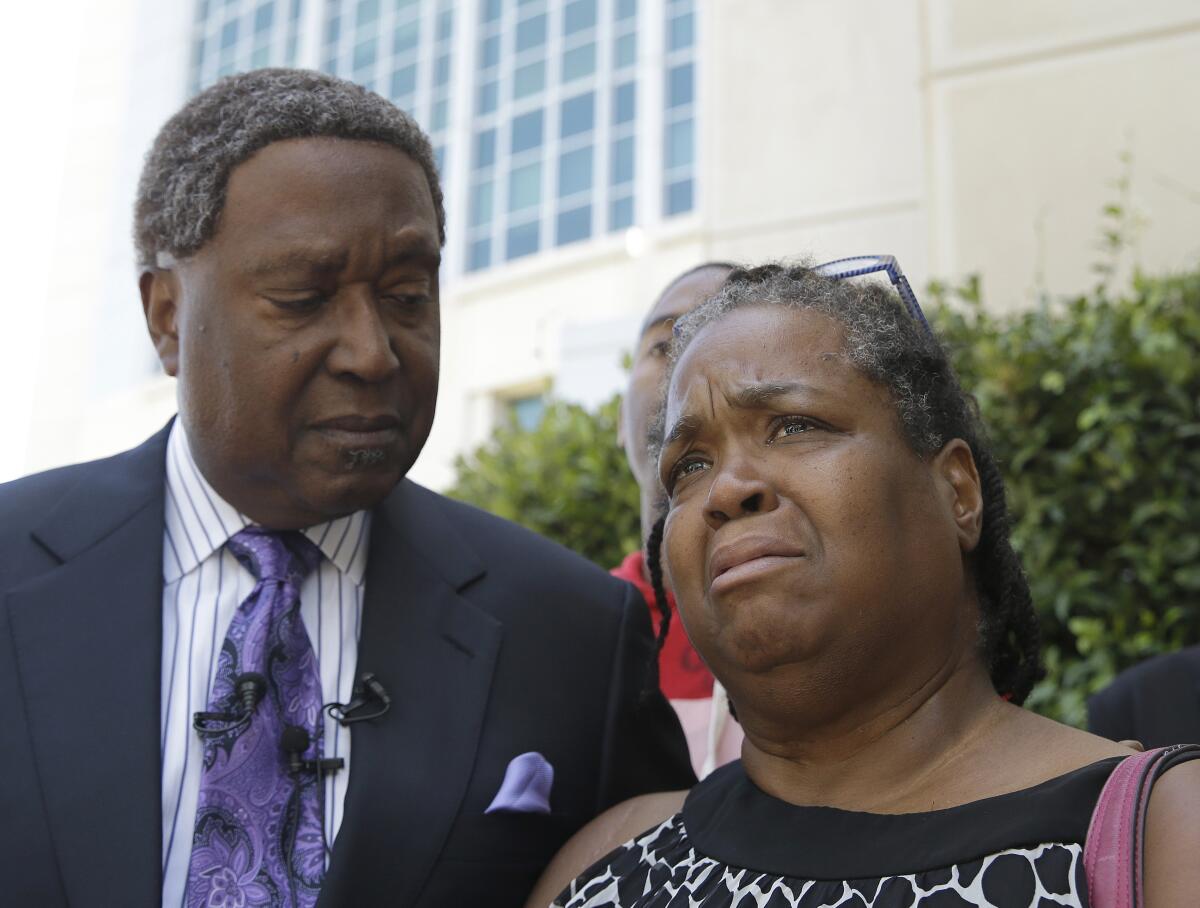 Brigett McIntyre, with attorney John Burris, tears up at a news conference on the police killing of her son in Sacramento