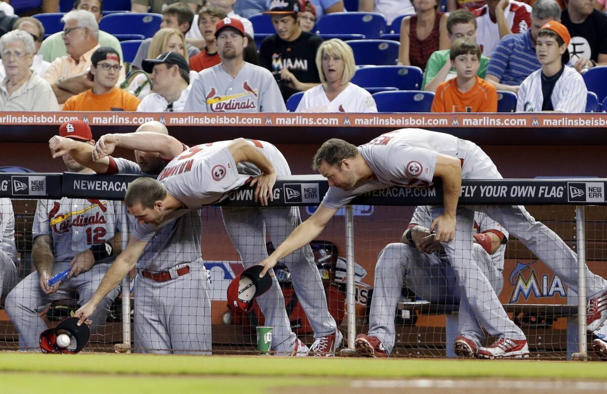 St. Louis pitcher Adam Wainwright snags a foul ball, beating out fellow pitcher Jake Westbrook during the first inning of the Cardinals' game against the Miami Marlins on Saturday.