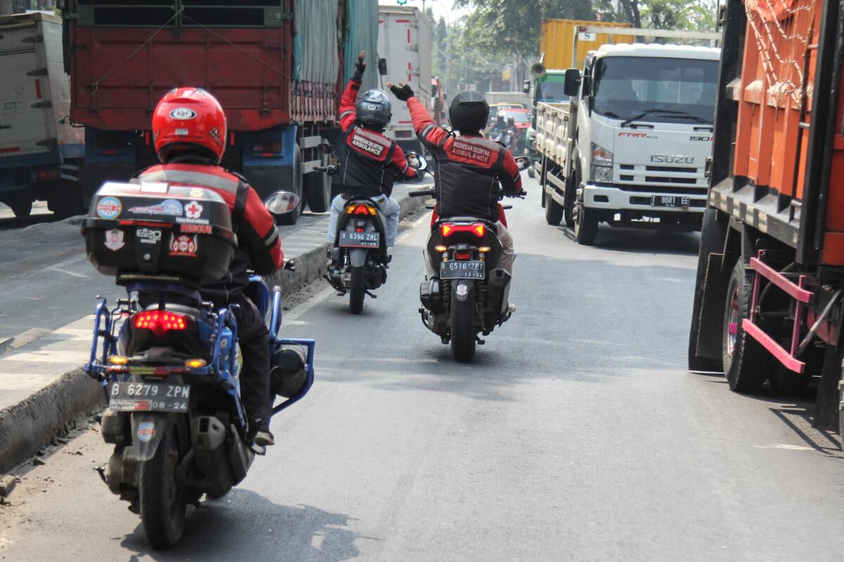 Three motorcycles travel down a street. 