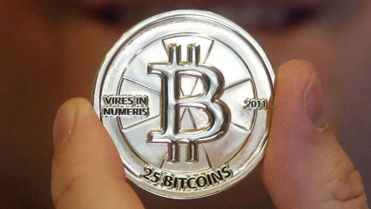 A man holds a token bearing the symbol of digital cryptocurrency bitcoin.