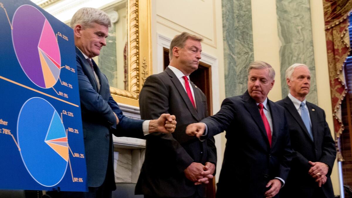 Sen. Bill Cassidy, R-La., left, and Sen. Lindsey Graham, R-S.C., second from right, with Sen. Dean Heller, R-Nev., second from left, and Sen. Ron Johnson, R-Wis., right, fist bump each other during a news conference in Washington on Sept. 13.