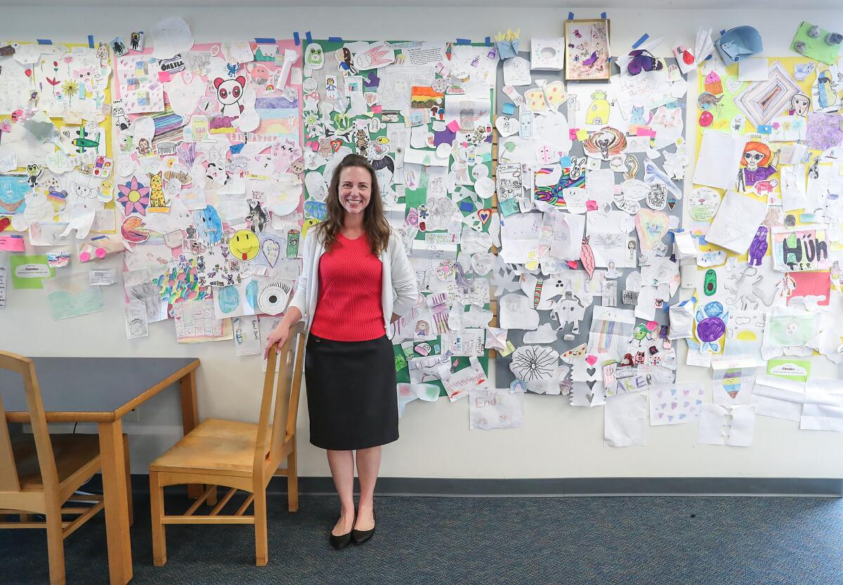 Library media technician Jacquelyn Casella stands with a few hundred of the Mariners Elementary Comicon artworks.