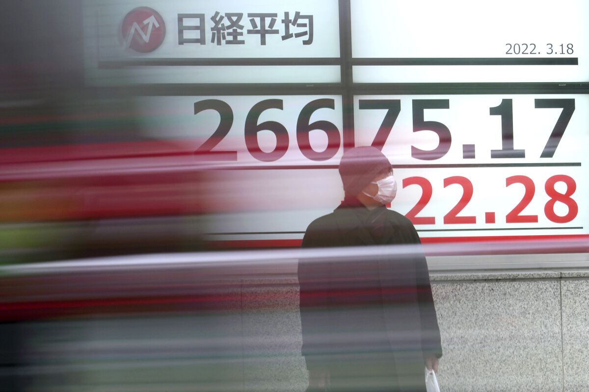 A man wearing a protective mask stands in front of an electronic stock board showing Japan's Nikkei 225 index at a securities firm Friday, March 18, 2022, in Tokyo. Shares were mostly lower in Asia on Friday after Wall Street extended a rally into a third day and oil prices pushed higher, surpassing $105 per barrel. (AP Photo/Eugene Hoshiko)