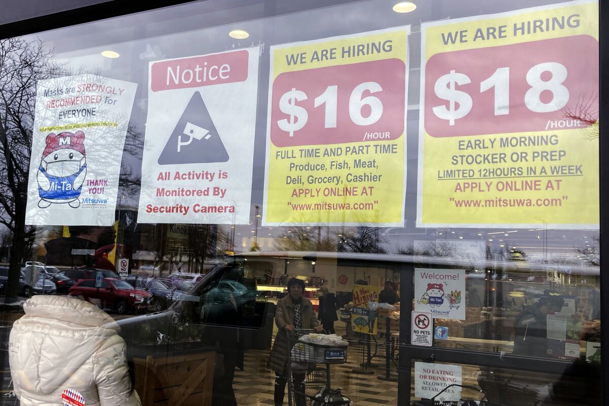 FILE - Hiring signs are displayed at a grocery store in Arlington Heights, Ill., Friday, Jan. 13, 2023. On Tuesday, the Labor Department reports on wages and benefits for U.S. workers during the October-December quarter. (AP Photo/Nam Y. Huh, File)