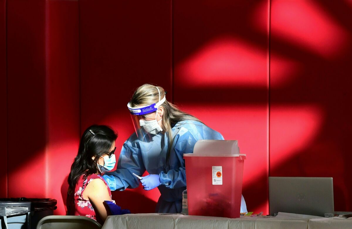 A registered nurse administers the COVID-19 vaccine to a woman.