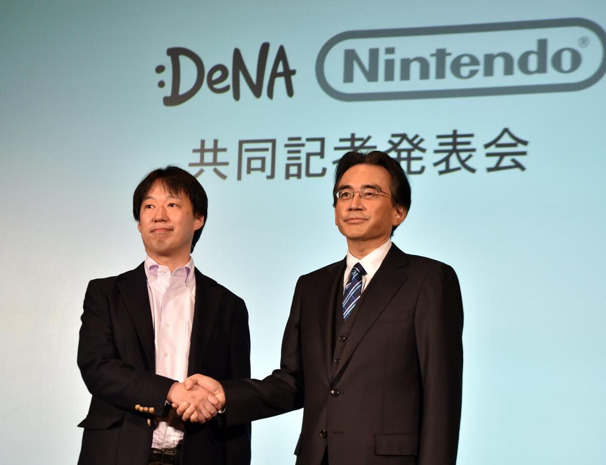 Japan's video game giant Nintendo President Satoru Iwata, right, with Japanese online game operator DeNA President Isao Moriyasu during a press conference in Tokyo on March 17, 2015.
