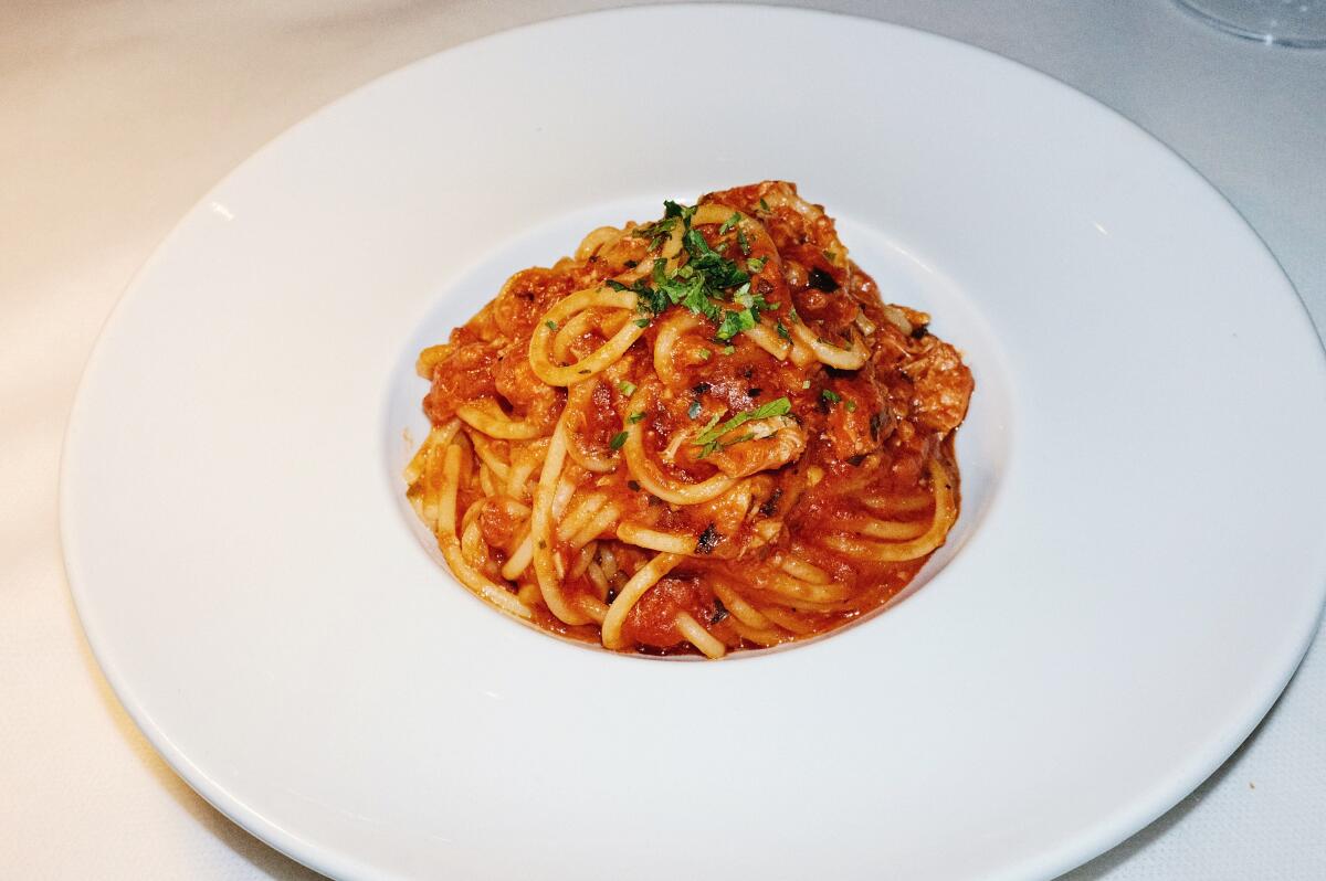 A small mound of spaghetti in tomato sauce in a white bowl on a white tablecloth at Osteria Mamma.