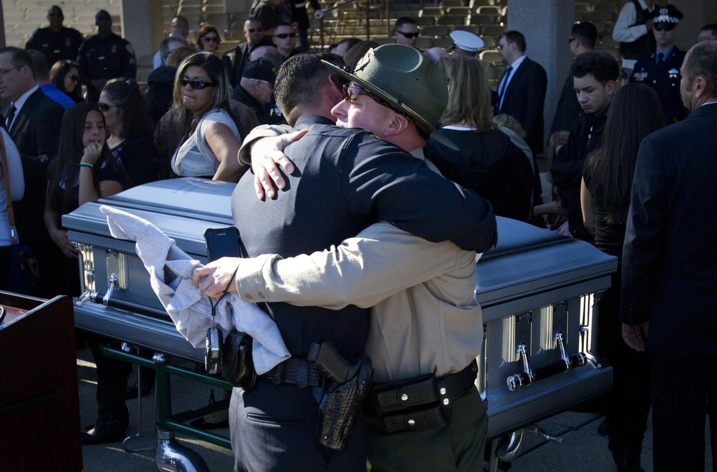 Law enforcement officers embrace at the casket of slain Riverside Police Officer Michael Crain after a memorial service at Riverside National Cemetery.