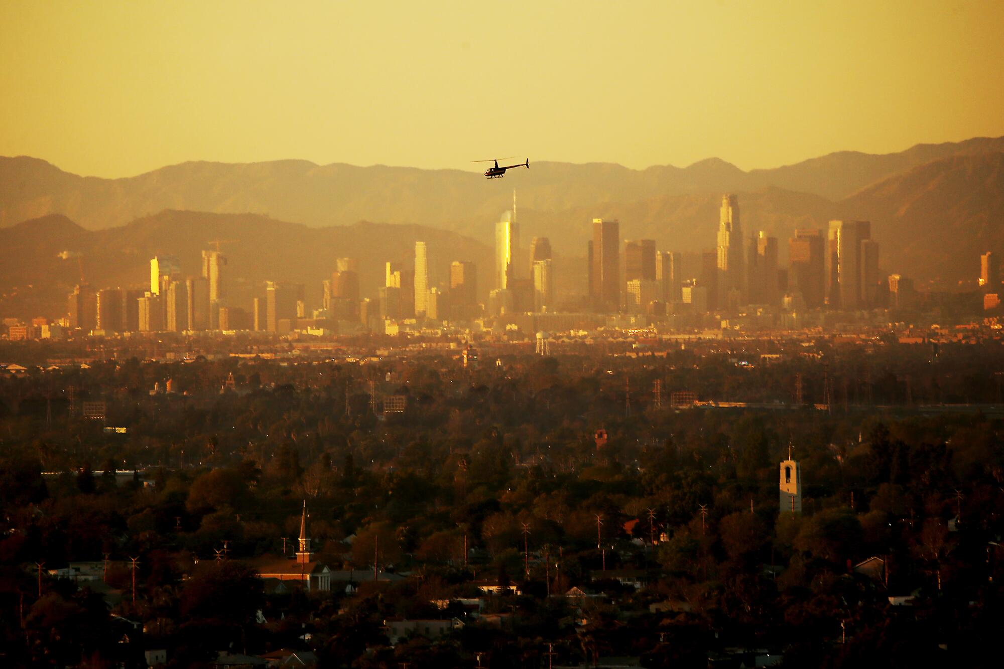 A helicopter flies across the hazy atmosphere of the Los Angeles Basin