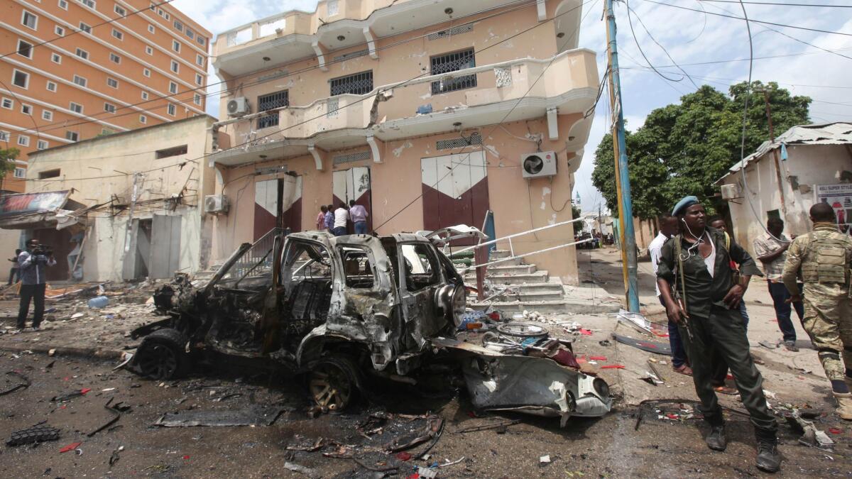 A Somali soldier stands on guard next to a destroyed car near a popular mall after a car bomb attack in Mogadishu, Somalia.