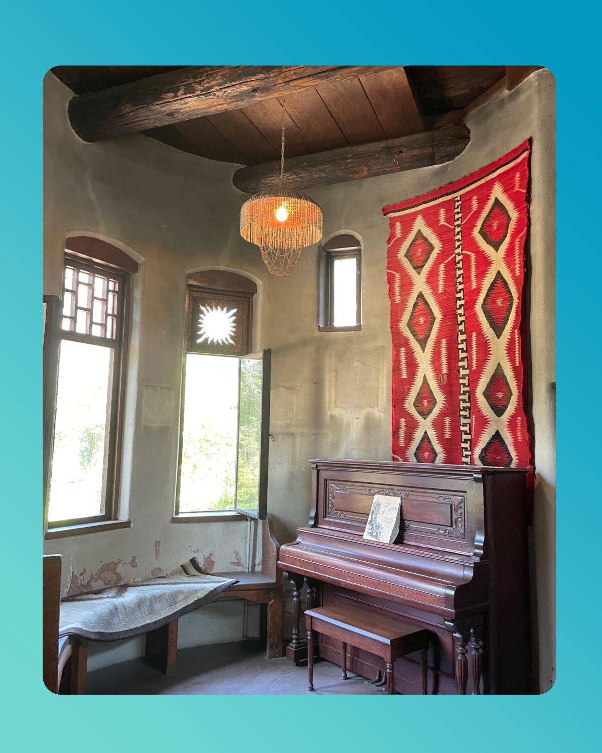 Room in the Lummis House with a piano and wall-hanging.