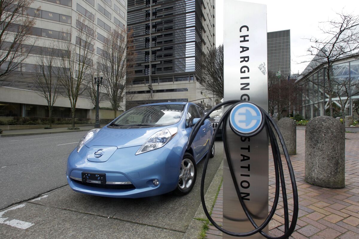 FILE - A car is parked by an electric charging station in downtown Portland, Ore., March 31, 2011. Oregon will temporarily suspend rebates for buying or leasing an electric vehicle for a year starting in May. The Oregonian/OregonLive reports the suspension comes because too many people are applying and the program is running out of money. (AP Photo/Rick Bowmer, File)