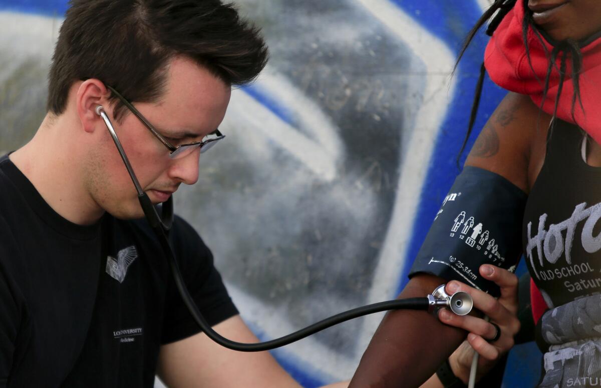 Dr. James Cunningham checks the blood pressure of a woman in downtown Los Angeles. A new study finds that the chances that an adult has seen a doctor in the last year vary greatly by state, from a low of 51.9% in Montana to a high of 84.1% in Vermont.