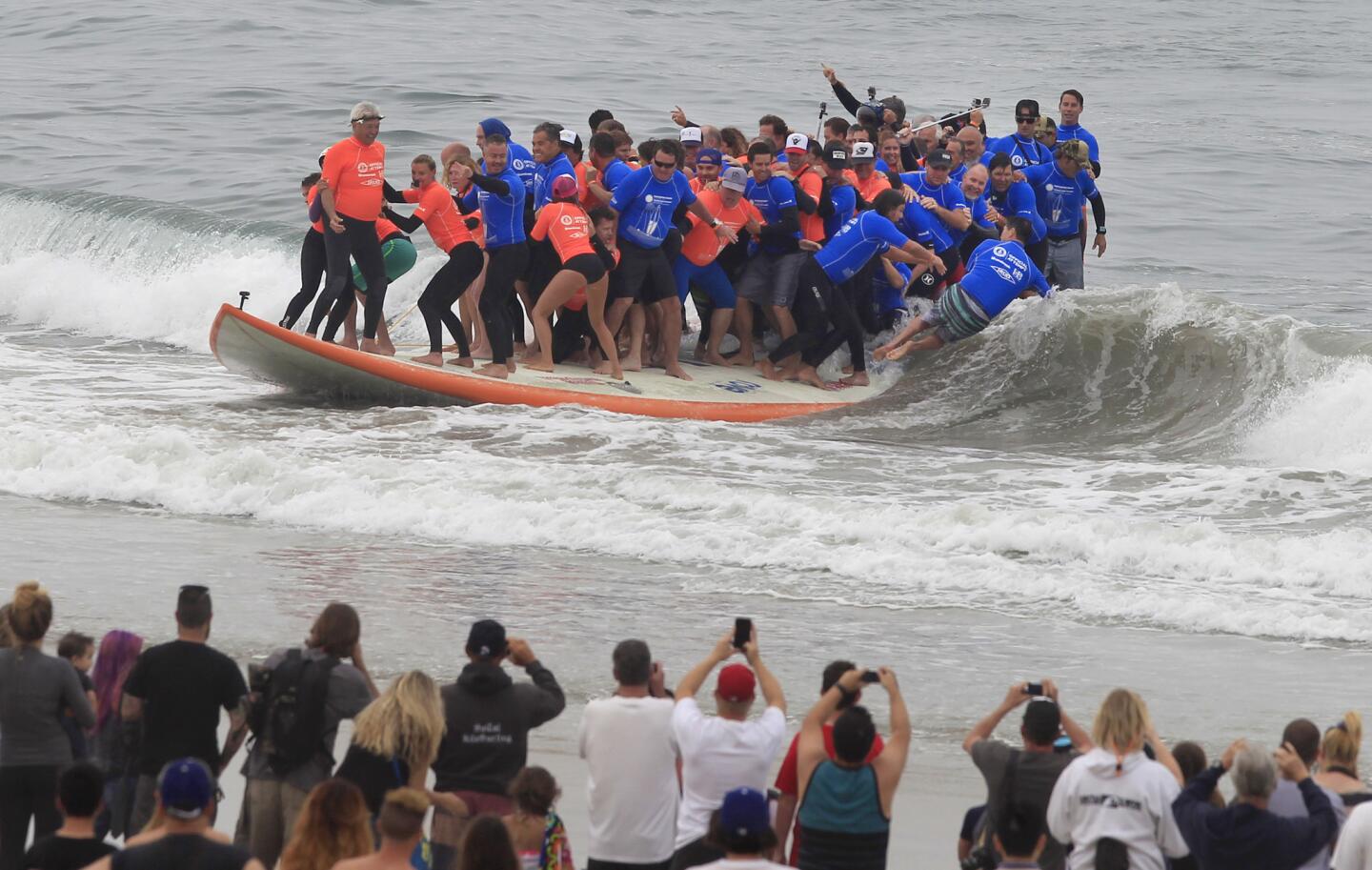 Sixty-six surfers attempt to break the record for most people on a surfboard and biggest surfboard, as crowds watch from the beach in Huntington Beach.