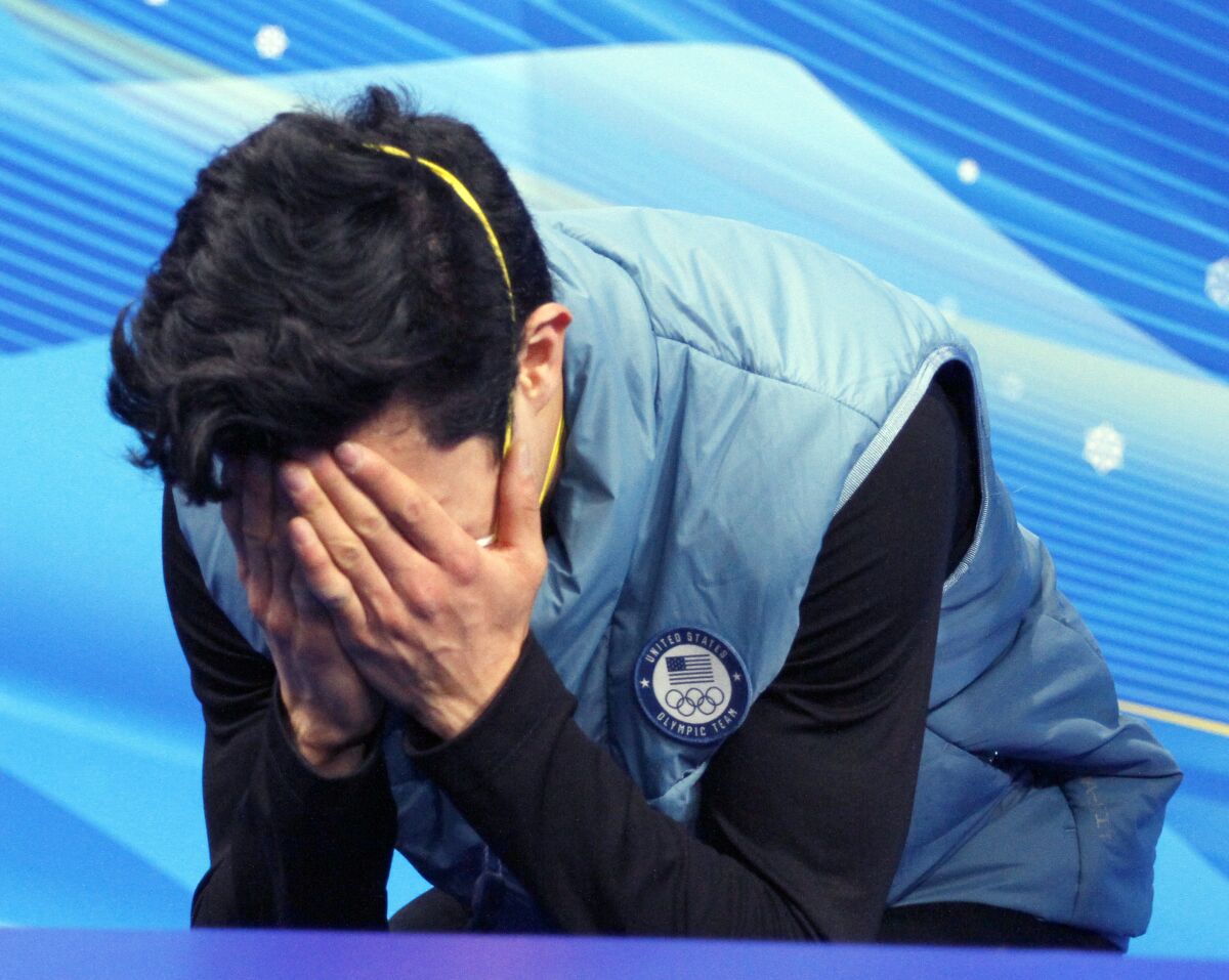 Nathan Chen covers his face with his hands after hearing his results from the short program Tuesday in Beijing.