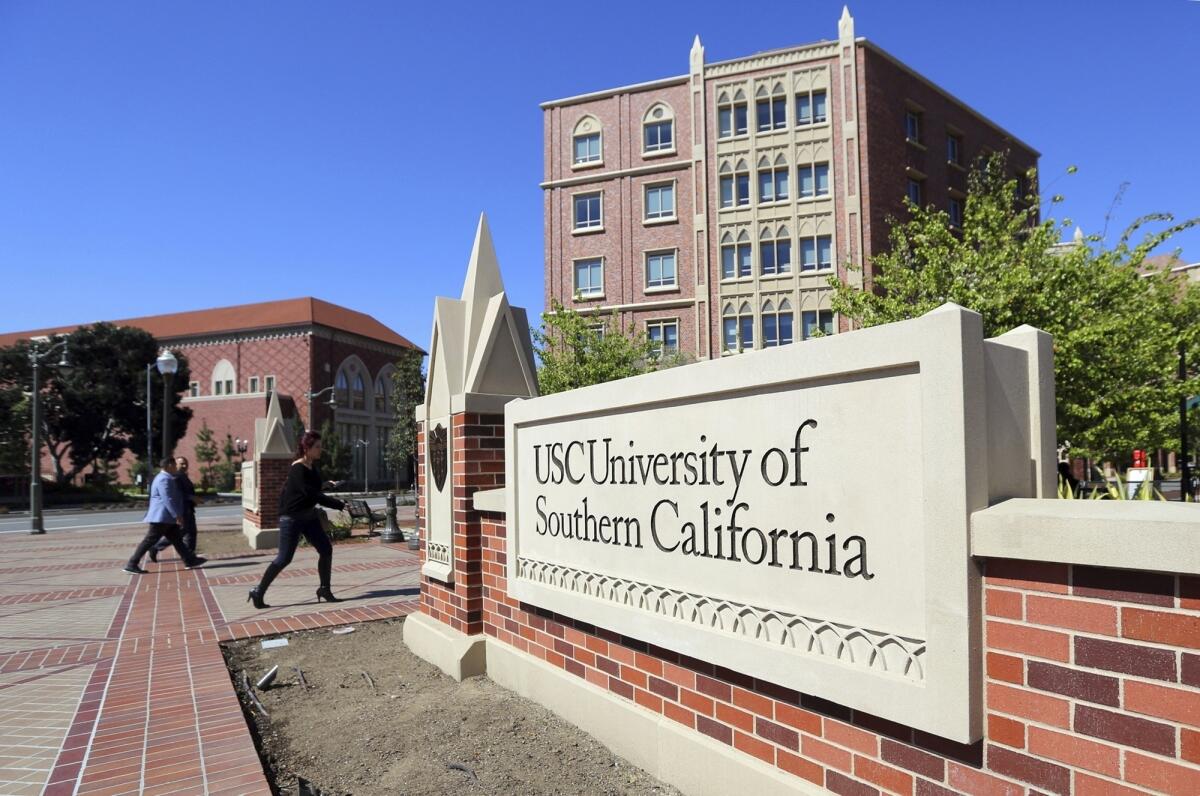 A stone sign that reads "University of Southern California" in the foreground, with buildings and students in the background.