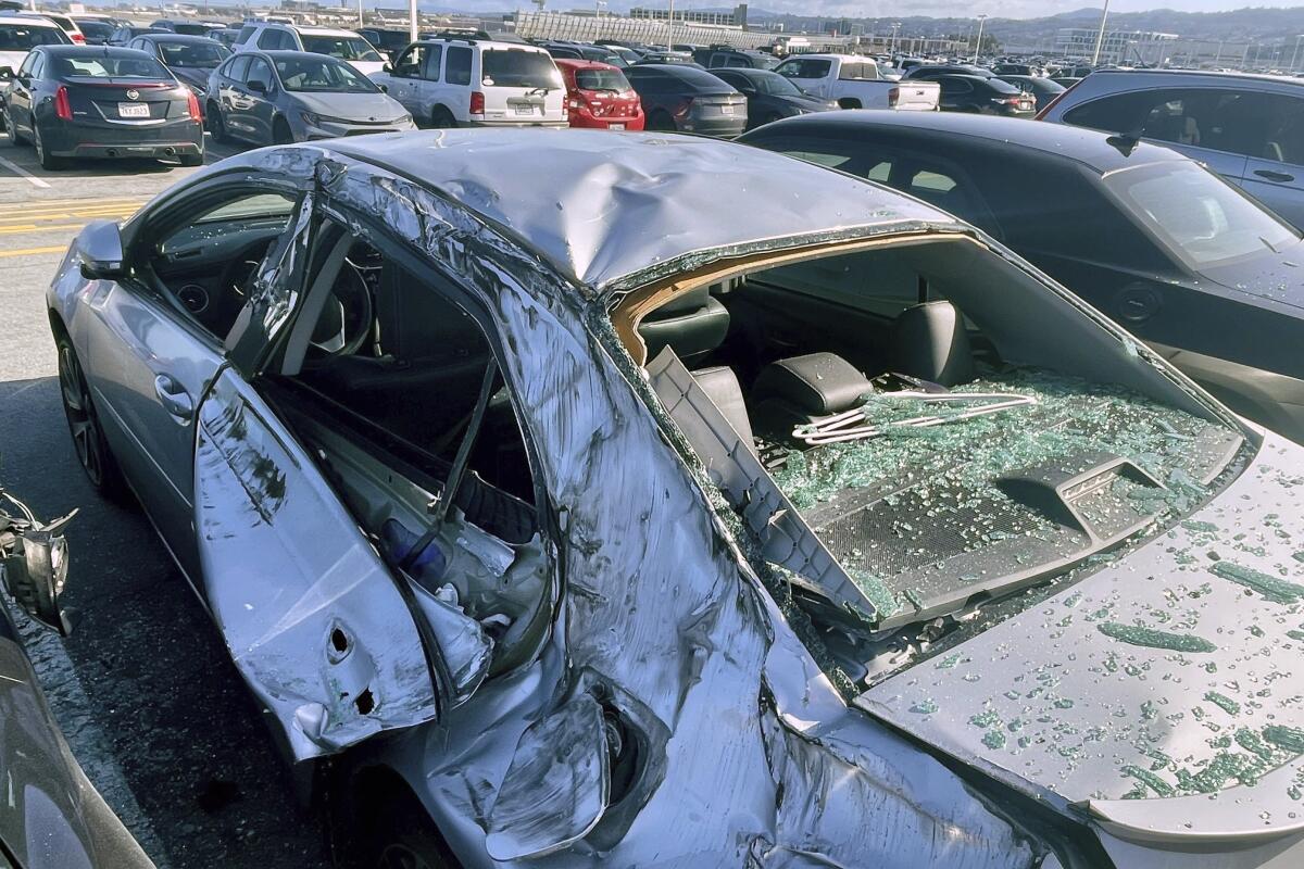 A damaged car is seen in a parking lot