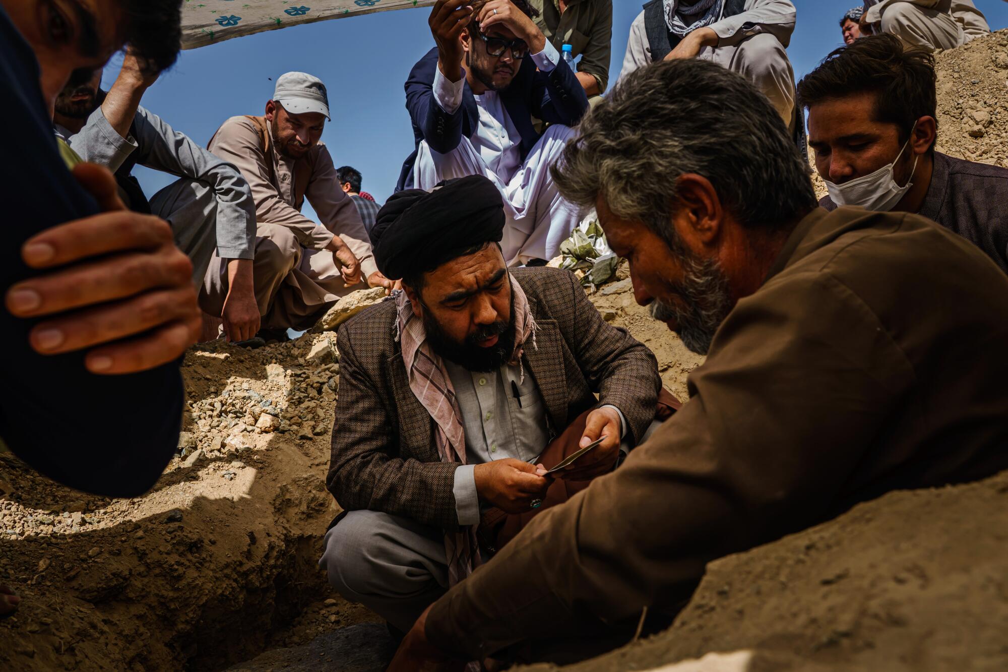 A man reads from a book beside a grave