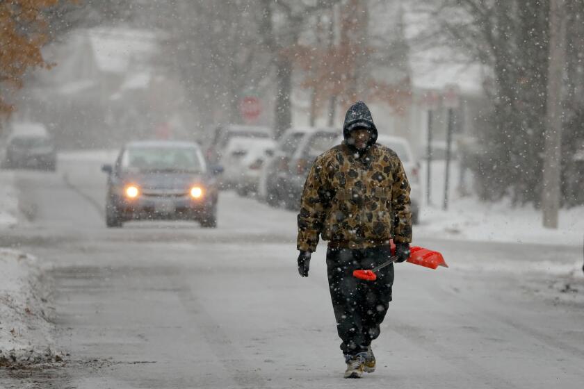 Bill Parham walks down an icy street in Maplewood, Mo., looking to clear snow off people's driveways and sidewalks on Monday, Dec. 16, 2019. The wintry weather was part of a storm system that hit parts of the Midwest and was expected to extend into the Northeast through Tuesday, the National Weather Service said. (David Carson/St. Louis Post-Dispatch via AP)