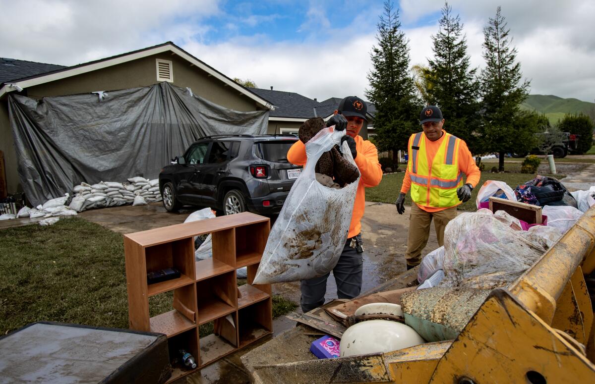 city workers removed mud soaked belongings from the curb in front of a house