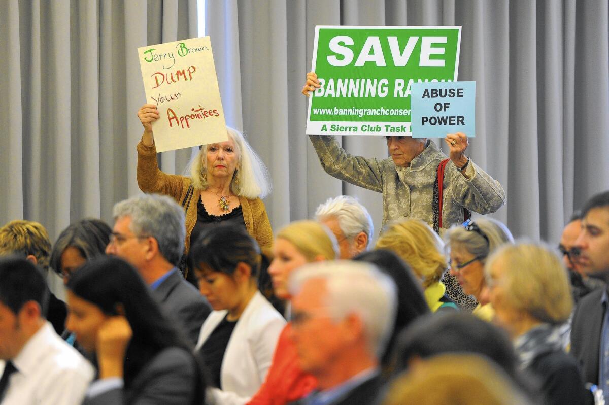 People hold protest signs in March at the first California Coastal Commission hearing since the firing of Executive Director Charles Lester.