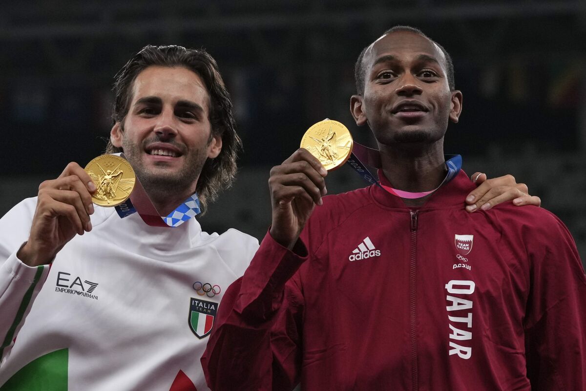 Joint gold medalists Mutaz Barshim, of Qatar, and Gianmarco Tamberi, left, of Italy pose for a photo following the men's high jump final at the 2020 Summer Olympics, Monday, Aug. 2, 2021, in Tokyo. (AP Photo/Francisco Seco)