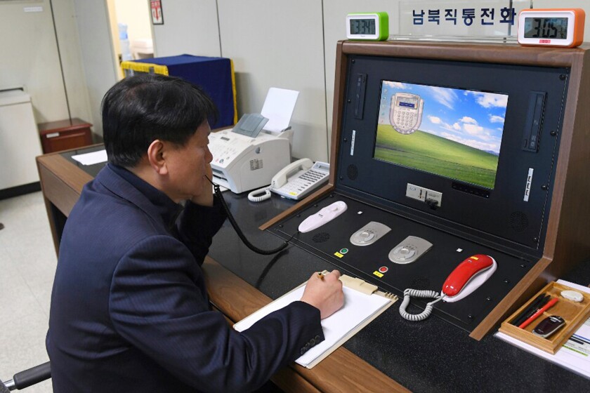 A South Korean official writes notes while talking on a phone.