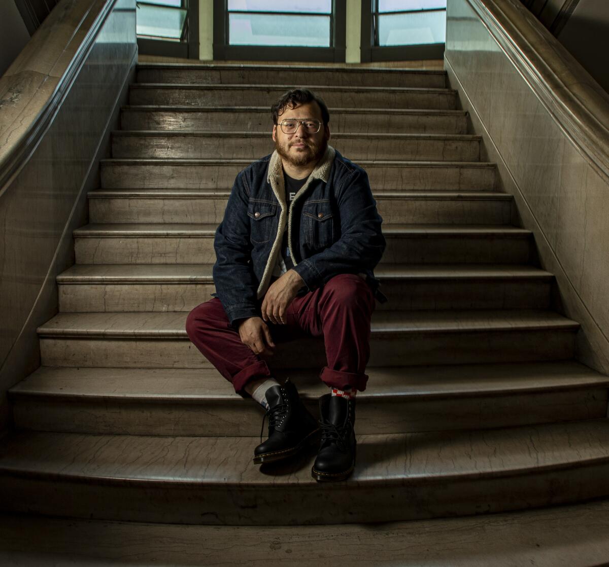 christopher oscar peña sits on the interior steps of an apartment building.