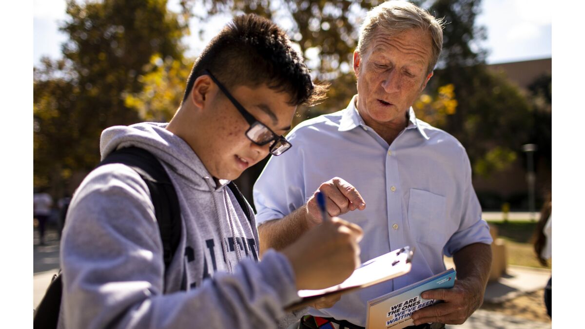 Tom Steyer helps Cal State Fullerton student Kevin Huy Nguyen, 18, fill out paperwork to register to vote.