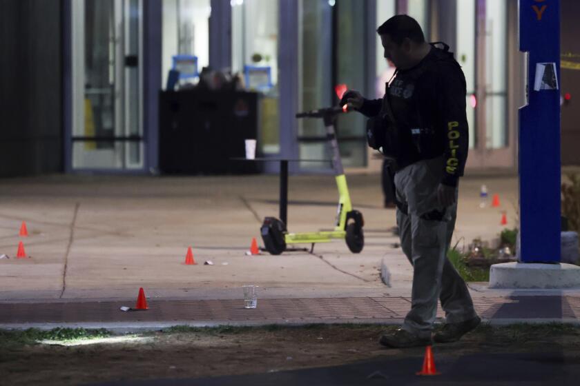 A police officer searches for evidence in front of a building at Morgan State University after a shooting, Wednesday, Oct. 4, 2023, in Baltimore. (AP Photo/Julia Nikhinson)