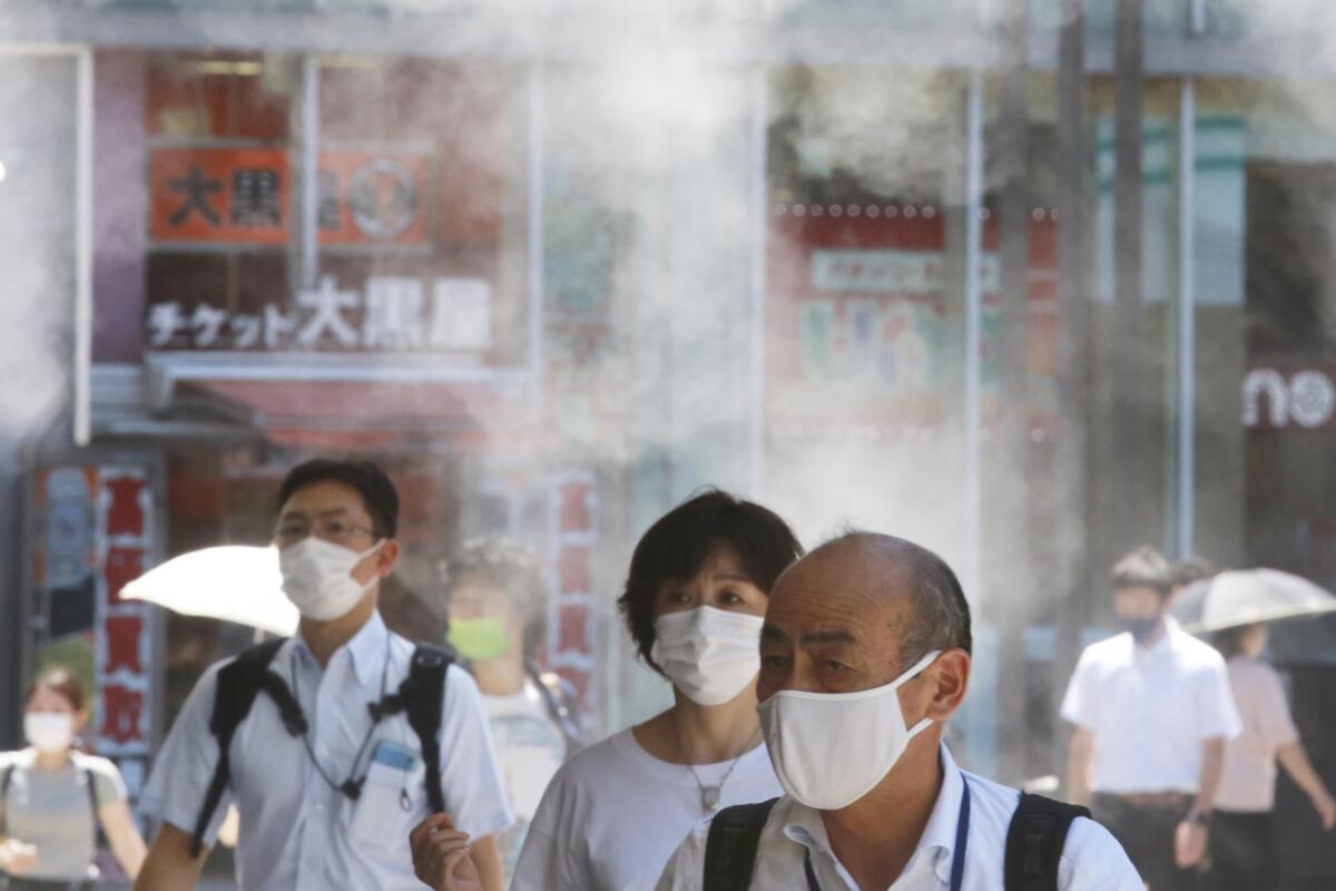 Masked pedestrians walk outside in Tokyo.