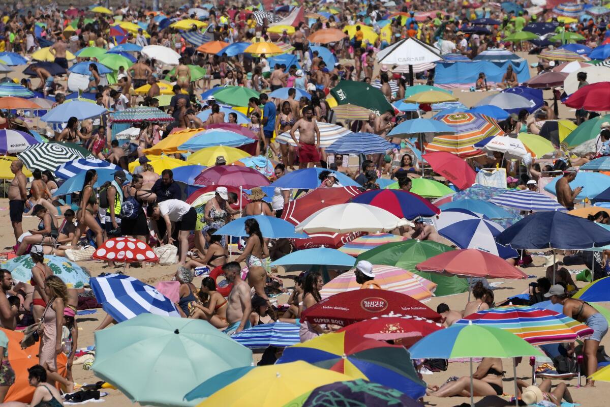 People crowd the Carcavelos beach, outside Lisbon, Friday, July 8, 2022. Portugal's government on Friday declared an eight-day state of alert due to the heightened risk of wildfires, as the drought-stricken country prepares for a heat wave packing temperatures as high as 43 degrees Celsius (109 degrees Fahrenheit). (AP Photo/Armando Franca)