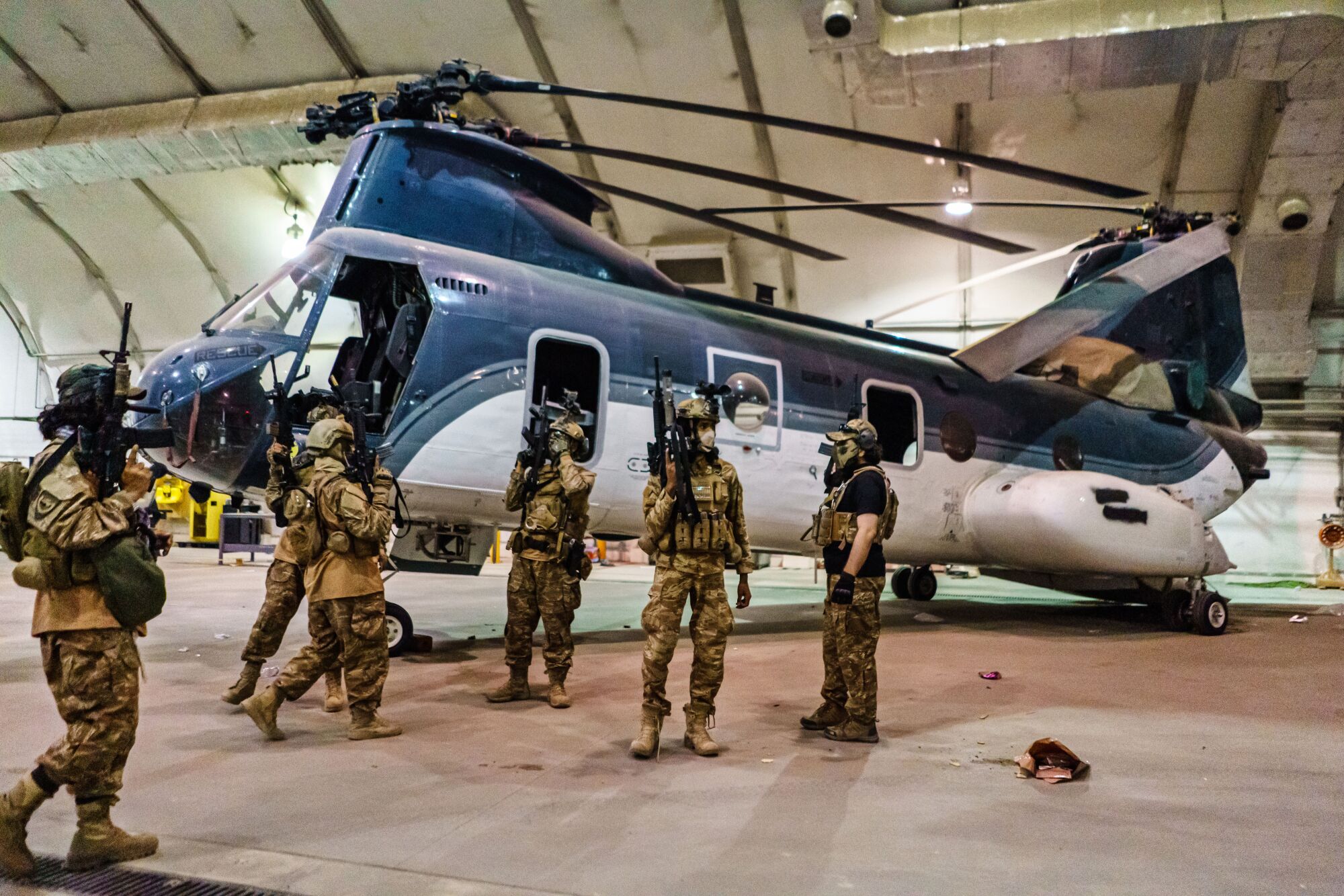 Fighters inside a hangar next to a military helicopter 