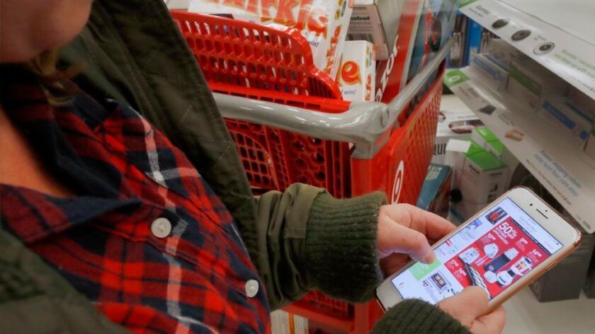 A shopper checks out deals on her smartphone Thanksgiving Day at a Target store in Orem, Utah.