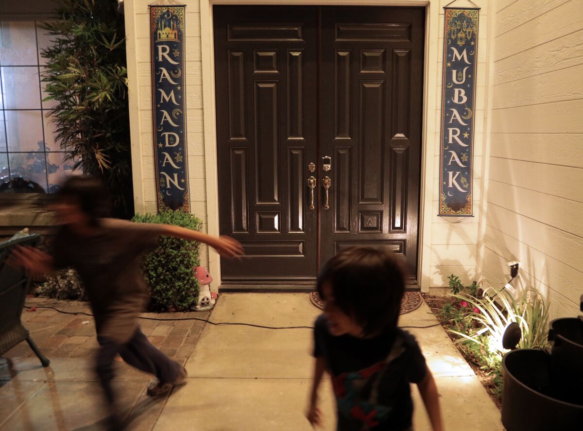 Kids running around in front of a doorway with Ramadan banners