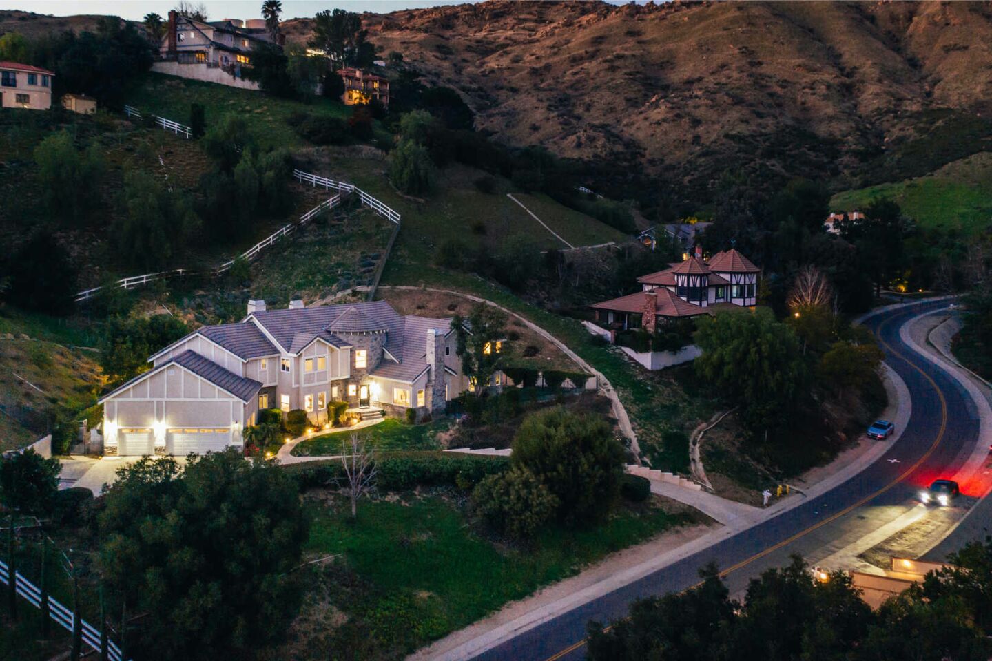 Aerial view of the two-story home amid hills, with a winding road in front.