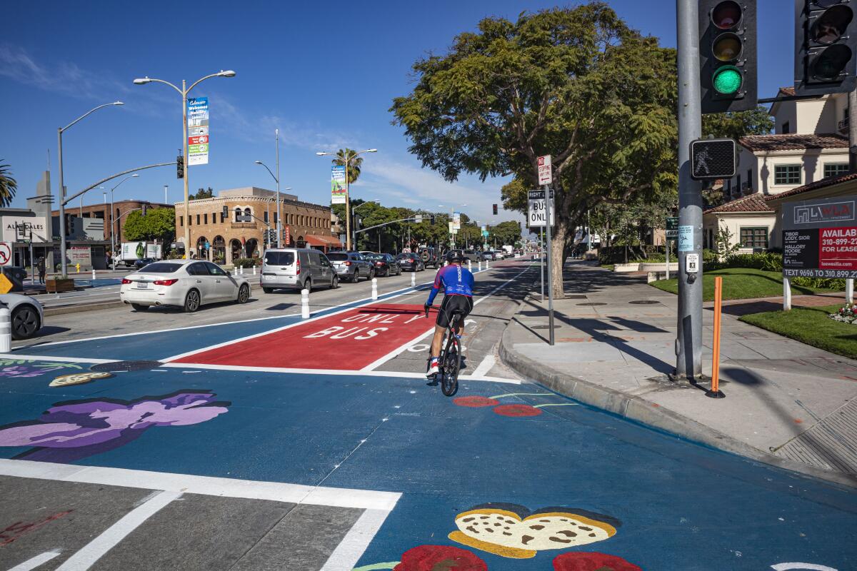A cyclist rounds a street corner as they rides in a bike lane on sunny day.