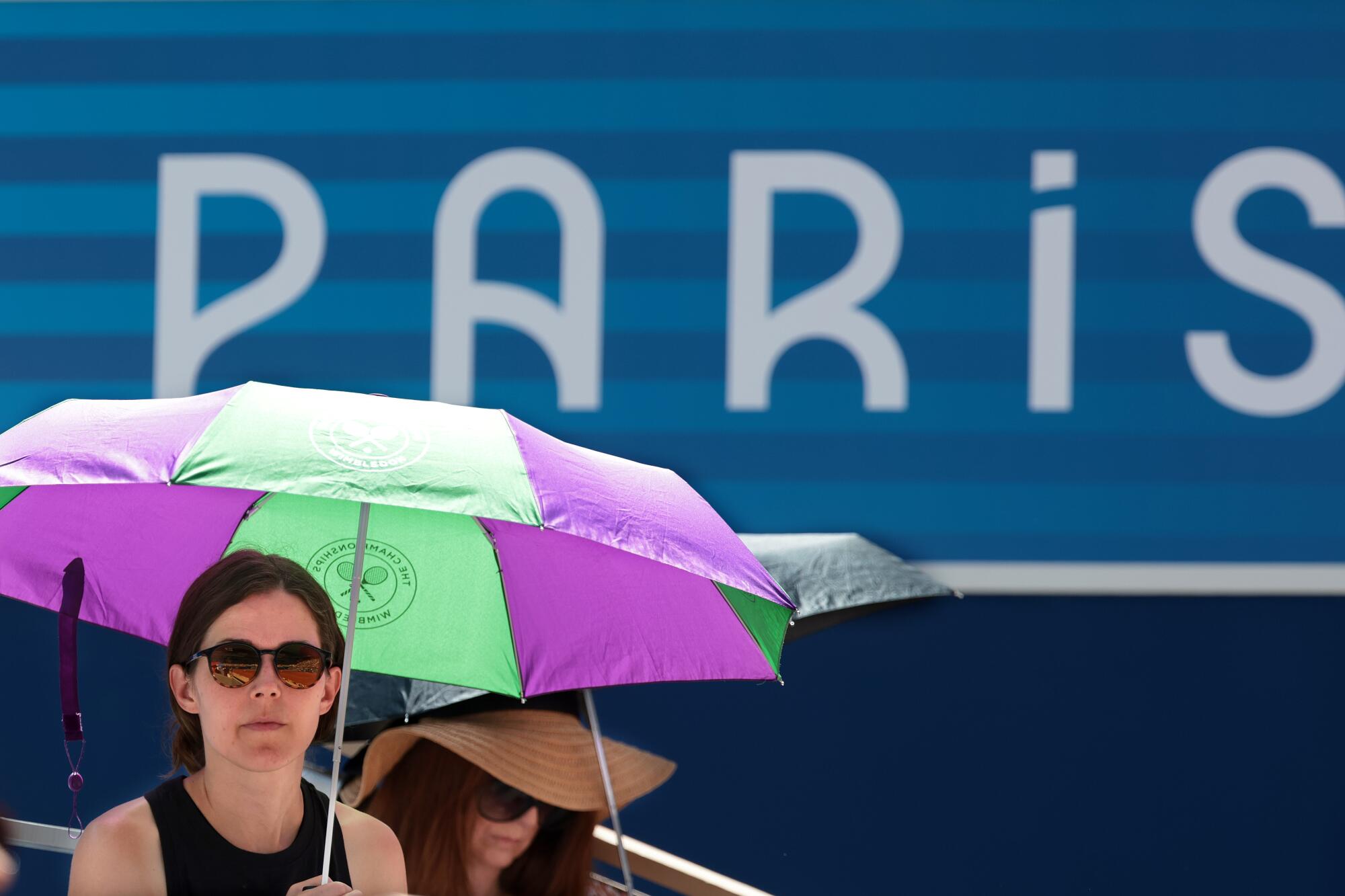 Fans try to stay cool while watching tennis at Roland Garros during the Paris Olympic Games.