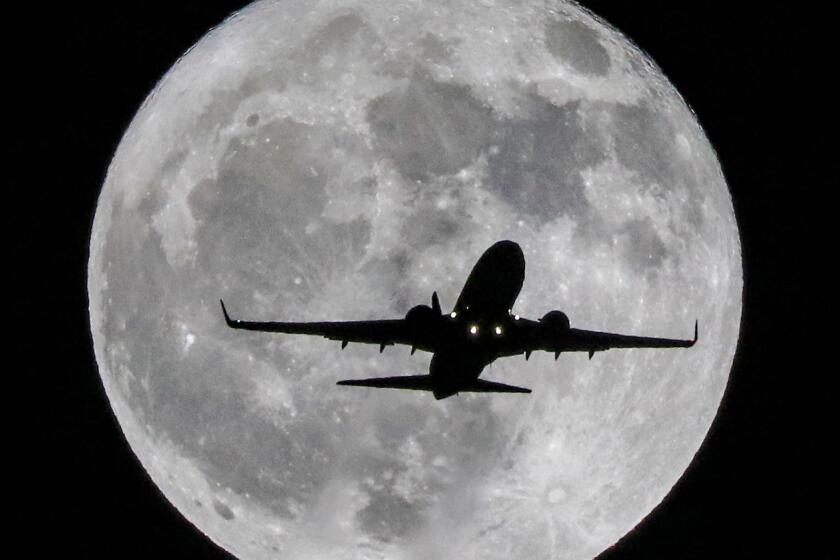 WHITTIER, CA., OCTOBER 14, 2018: A jetliner on its way to LAX flies low and slow over the city Of Whittier, California October 14, 2018, with the rising full moon behind it (©Mark Boster-2018)