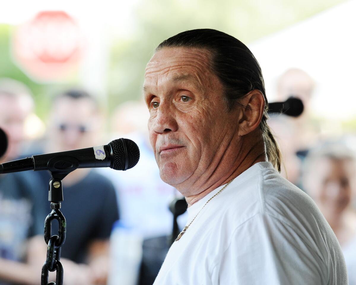 Iron Maiden drummer Nicko McBrain stands at a microphone in an outdoors setting