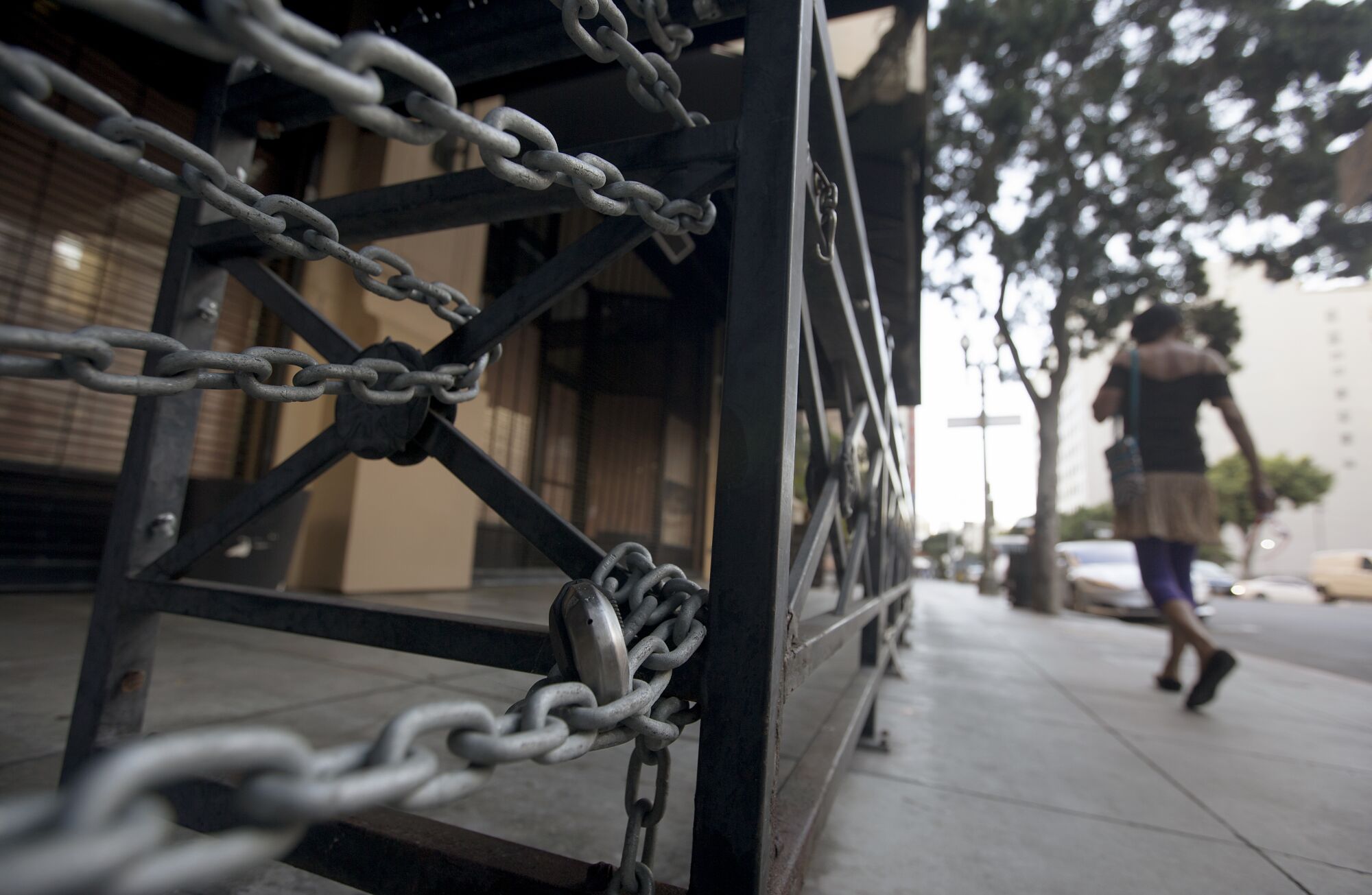 A woman walks past a shuttered restaurant in downtown Los Angeles