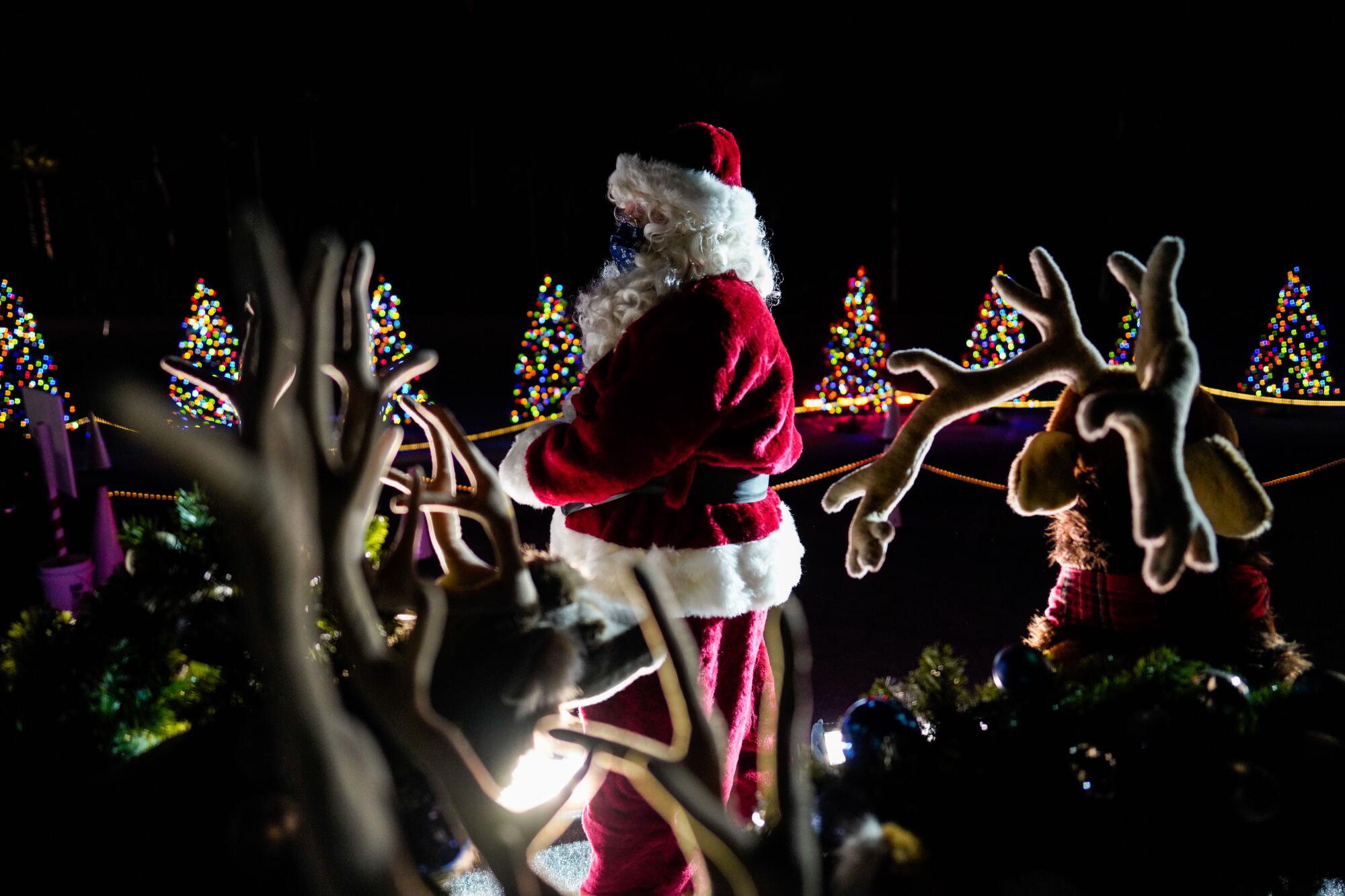 A performer dressed as Santa Clause greets cars making their way through the Dodger's Holiday Festival